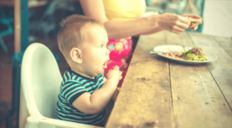 Criança pequena sentada na cadeira comendo