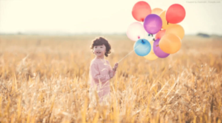 Criança no campo segurando balões