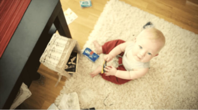 Criança sentada no tapete brincando com algumas coisas